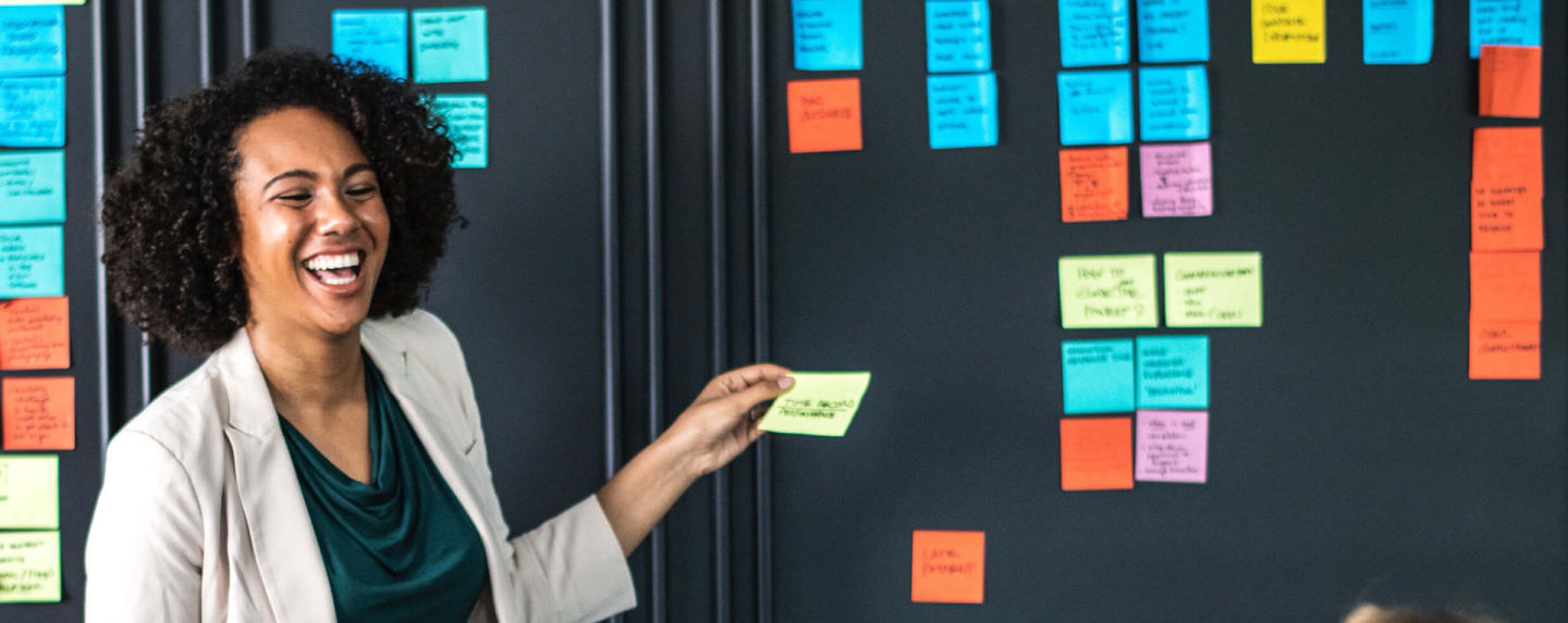A cheerful lady placing a sticky note on a board
